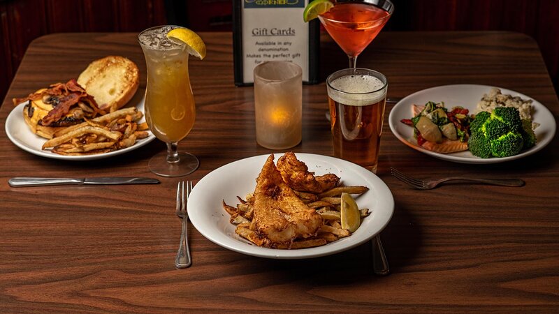 Mutiple plated entrees and drinks with focus on Fish & Chips entree